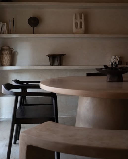 Une salle à manger : pièces posées sur des étagères de plâtre, table ronde, chaise noire